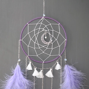 Detail of moon pendant and purple feathers on a handmade dreamcatcher wall hanging