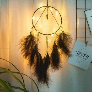 Detail of bohemian dreamcatcher with warm LED lights, dark feathers, and natural crystal stone