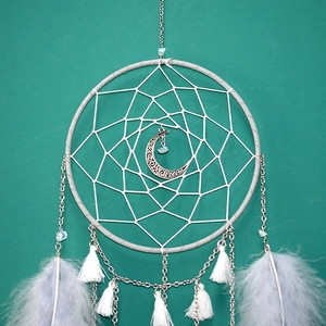 Detail of mooncatcher wall hanging with white weaving, silver moon pendant and feathers