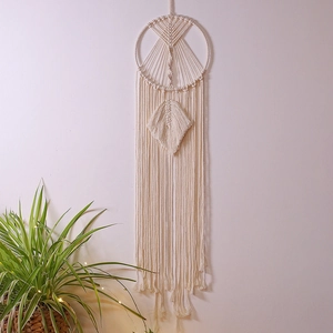 Macro shot of a bohemian macrame dream catcher with detailed cotton weaving and leaf pendant