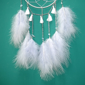 Detailed close-up of white feathers and blue beads on a moon dream catcher