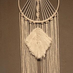 Detail of bohemian macramé wall hanging showing intricate handmade knots and cotton leaf fringe
