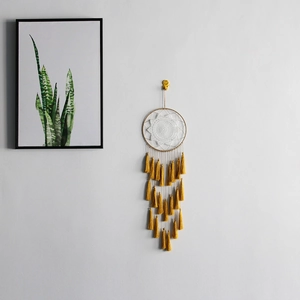 Detail of bohemian dream catcher featuring white crochet webbing and yellow tassels