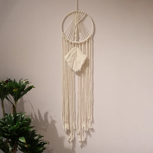 Detailed close-up of handmade cream cotton macrame wall hanging with leaf weave pattern