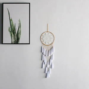 Close-up of white macrame dream catcher with multi-layered tassels on a minimal wall