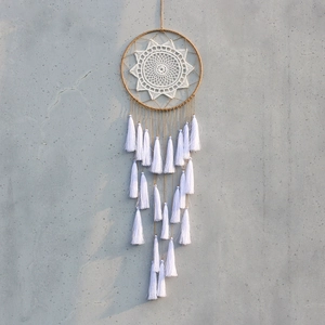 Macro shot of handcrafted bohemian dreamcatcher featuring white lace and long rope tassels