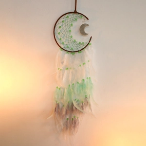 Detail of moon-shaped dream catcher with green beads and gradient pastel feathers