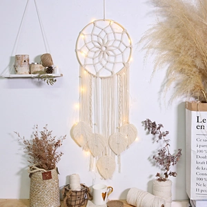 Close-up of bohemian handmade woven leaf wall hanging with warm LED string lights