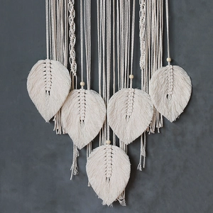 Detail of five handmade macrame leaf patterns with wooden beads on a woven wall hanging