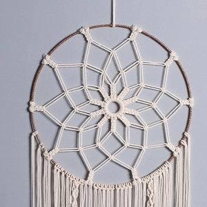 Macro shot of hand-woven star pattern and cream cotton tassels on bohemian wall hanging