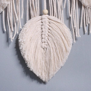 Macro shot of handcrafted macrame leaf wall hanging with cotton fringe and wood bead