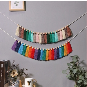 Detail of colorful macrame fringe garland with wooden beads on a minimalist wall decor
