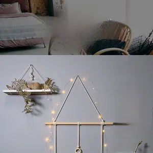 Detail of hand-woven cotton macrame wall hanging with wooden stick and fairy lights