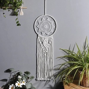 Detailed close-up of handmade white cotton macrame dreamcatcher with mandala weave pattern