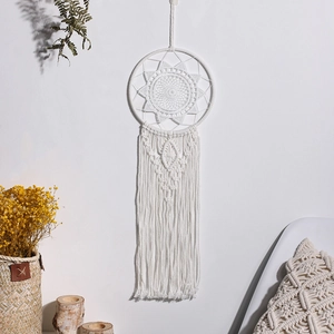 Detailed view of handmade white boho dreamcatcher with cotton fringe on a wall