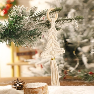 Close-up of handmade macrame Christmas tree with wood beads and tassel on snowy branch
