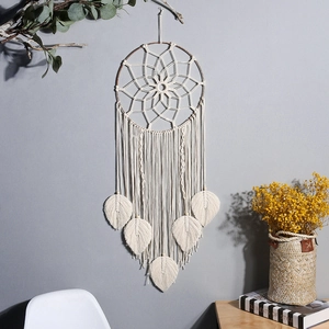 Bohemian handmade macrame wall hanging with woven leaf tassels on a grey wall background