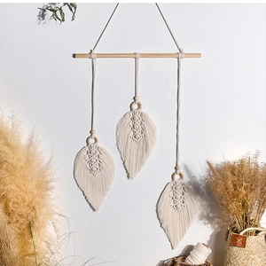 Detail of bohemian hand-woven cotton leaf tapestry with wooden beads on a white wall