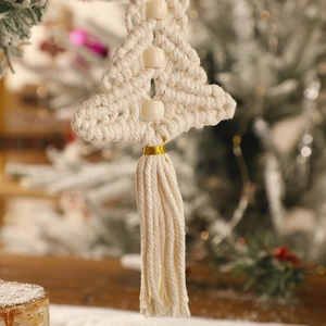 Close-up of handmade boho macrame Christmas tree with wood beads and gold thread fringe