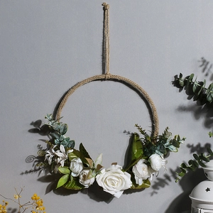 Detail of Nordic artificial wreath with white roses and eucalyptus on a textured wall