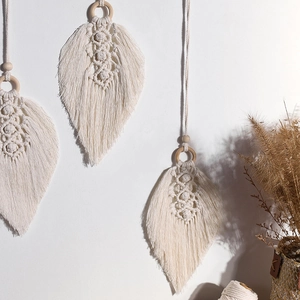 Handmade boho macrame leaf wall hanging with cotton rope and wooden beads on a white wall