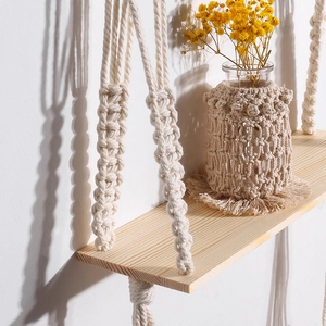 Detail of bohemian wooden wall shelf with handcrafted cotton rope and decorative vase