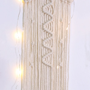 Detailed close-up of woven cotton tassels and warm LED fairy lights on a dreamcatcher