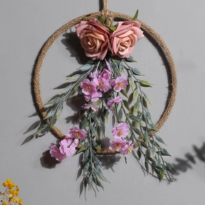 Dettaglio di rose finte rosa e fiori viola su una ghirlanda rustica in corda di canapa