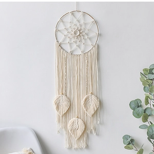 Detail of ivory woven dreamcatcher featuring macrame leaf tassels and wooden beads decor
