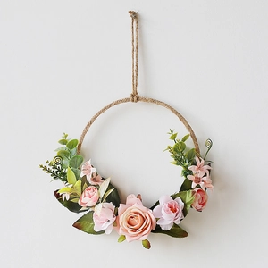Dettaglio di ghirlanda di rose artificiali con fiori rosa e corda di canapa rustica