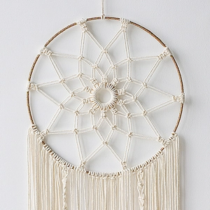 Detailed close-up of handmade boho dreamcatcher with cream cotton rope and gold ring