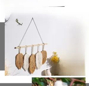 Detail of leaf-shaped woven cotton wall hanging with wooden rod and neutral feathers