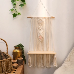 Detail of bohemian hand-woven cotton macrame wall shelf with natural pink crystal stones