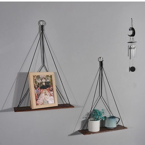 Detail view of rustic dark wood wall shelves with black ropes and hanging metal rings