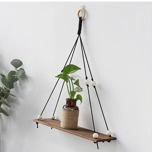 Detail view of walnut wood floating shelf with black woven rope and white wooden beads
