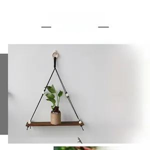 Detail of wooden floating shelf with black hanging rope and decorative light wood beads