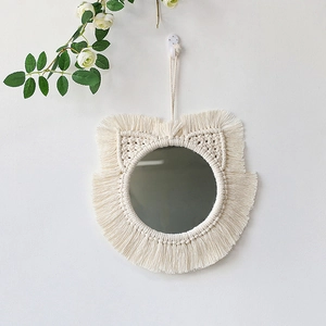 Detail of macrame cat ear wall mirror with bohemian fringe tassels on white wall