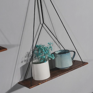 Nordic hanging wood shelf with black ropes and decor items on a minimalist gray wall