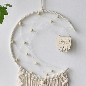 Detail of bohemian moon dream catcher with woven cotton rope and wooden owl pendant