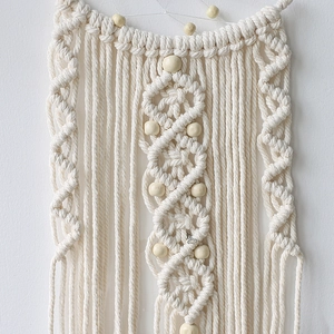 Detailed close-up of handmade bohemian woven wall hanging with cotton rope and wood beads