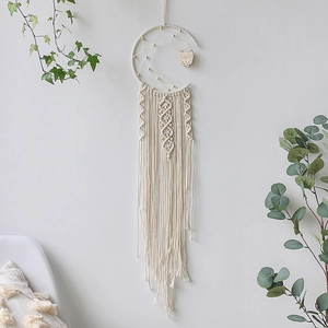 Detail of moon-shaped woven dreamcatcher with macrame tassels and wooden owl ornament