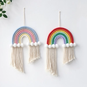 Detail of handmade cotton rope rainbow wall hanging with soft tassels and pom poms