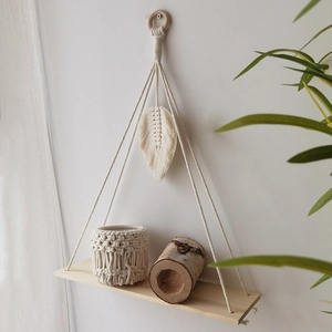 Detail of bohemian macrame wall shelf with woven leaf pattern and wooden platform