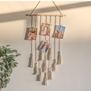 Detail of woven cotton wall hanging with wooden clips and tassels for photo display
