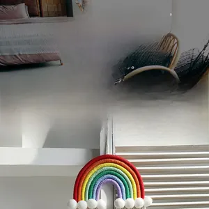 Detail of handmade rainbow wall hanging with colorful cotton cords and white pom-poms
