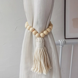 Detail of minimalist wooden bead curtain tieback with handcrafted white cotton fringe tassel