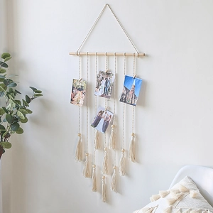 Close-up of bohemian woven tapestry with wooden photo clips and tassel details