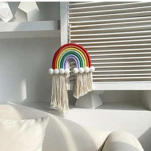 Detail showing colorful handmade rainbow tapestry with soft cotton tassels and white pom poms