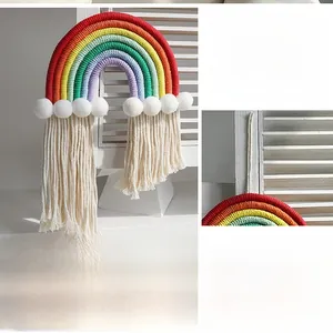 Close-up of handmade woven cotton rainbow wall hanging with white pompoms and long tassels