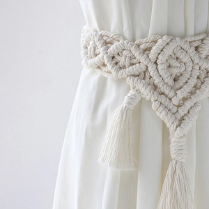 Detail of bohemian ivory cotton curtain tieback with woven texture and fringe
